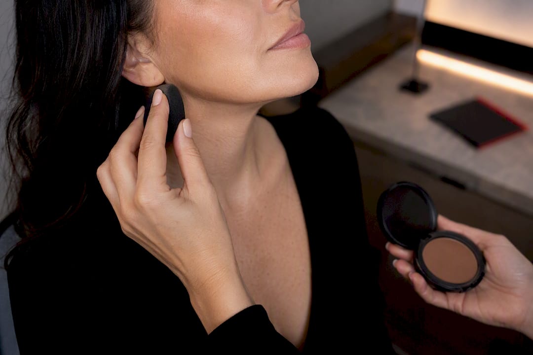 Hands blending contour beneath jawline